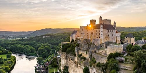 Château médiéval perché sur une falaise rocheuse dominant la vallée de la rivière au coucher du soleil près d'Eymet, France