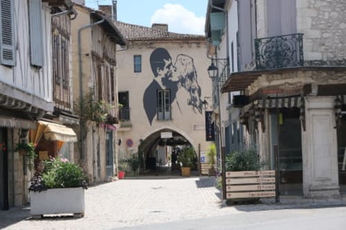Rue pavée pittoresque d'Eymet avec bâtiments historiques et street art à l'Hôtel les Vieilles Pierres
