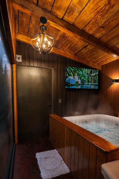 Lujosa sala de spa con bañera de hidromasaje en Cabañas el Encanto, vigas de madera, televisor de pantalla plana y vistas al jardín