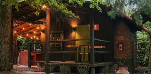 Cabaña rústica de madera en Cabañas el Encanto con luces cálidas, fachada de ladrillo y jardín bosque en Las Vigas