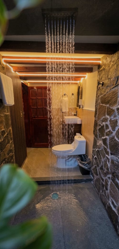 Modern bathroom with rainfall showerhead, toilet, sink, and warm lighting at Cabañas el Encanto in Las Vigas de Ramírez,