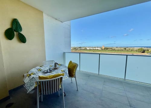 Appartamento con balcone in altura a Bari: tavolo da pranzo, vista mare e paesaggio costiero oltre la ringhiera
