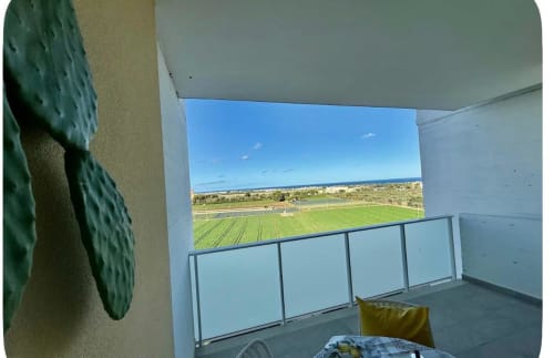 Vista dal balcone dell'appartamento dell'aeroporto di Bari con vista mare, campi verdi e ringhiera moderna che si affaccia sulla campagna