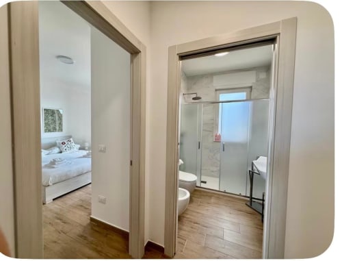 Vista moderna del corridoio dell'appartamento dell'aeroporto di Bari con camera da letto e bagno ensuite con doccia in vetro