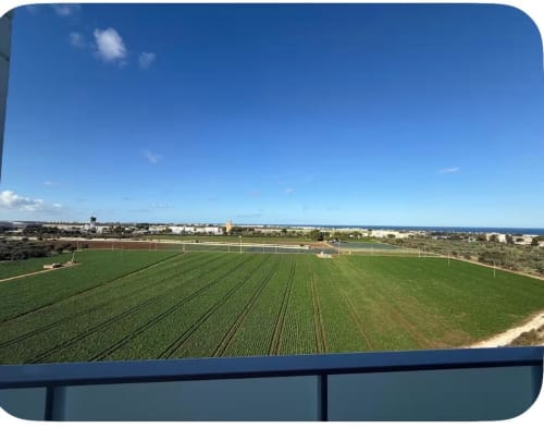 Vista aerea dei campi agricoli verdi vicino agli appartamenti dell'aeroporto di Bari con vista mare, cielo blu e paesaggio costiero