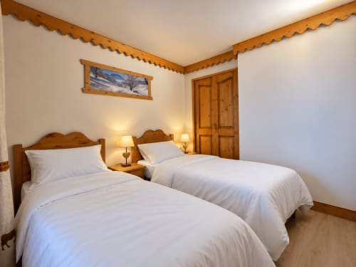 Chambre twin avec lits en bois et draps blancs à La Plagne Ski Confort, vue montagne et ambiance alpine chaleureuse
