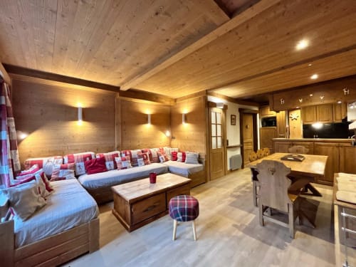 Séjour moderne avec lambris en bois, banquette intégrée, foyer et cuisine à La Plagne