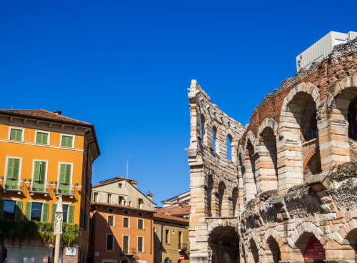 L'Arena di Verona, anfiteatro romano storico, circondata da edifici italiani colorati sotto un cielo azzurro
