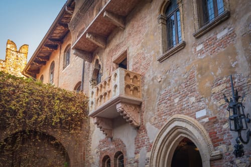 Facciata medievale in mattoni di B&B a Verona con balcone ornato, portale ad arco e muri ricoperti di edera