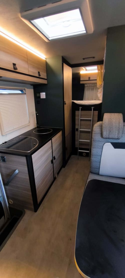Interior de la caravana Gozamena en Corralejo con cocina, zona de comedor y dormitorio con tragaluz