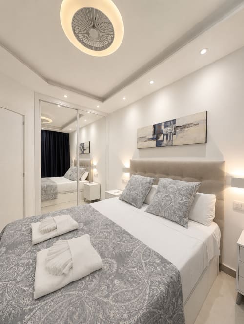 Modern bedroom at Manage Home Tenerife in Costa Adeje with mirrored wardrobe, neutral décor, and ceiling fan