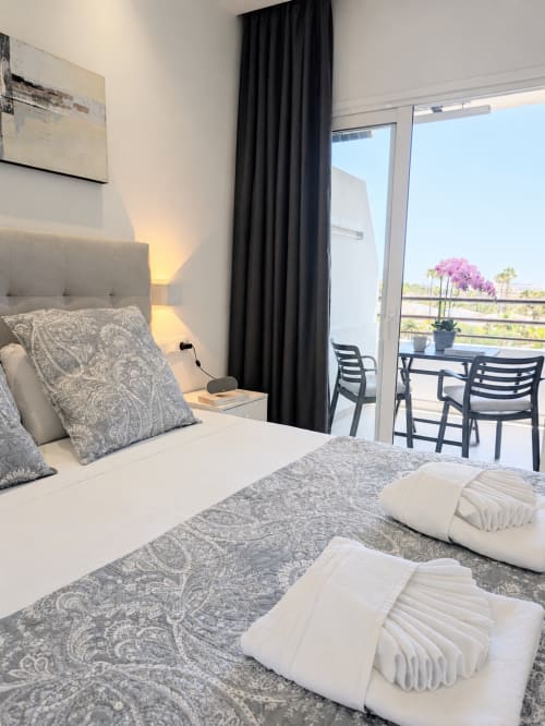 Modern bedroom at Manage Home Tenerife with sea view balcony, gray patterned bedding, and black curtains in Costa Adeje