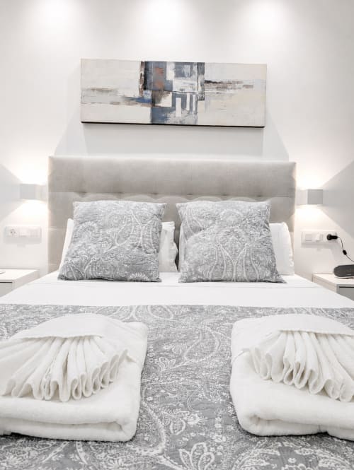 Modern beige bedroom with padded headboard, patterned pillows, and white wing decorations at Manage Home Tenerife, Costa