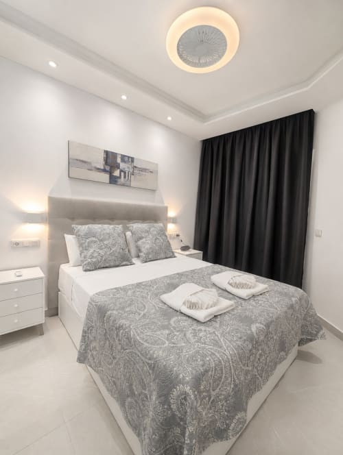 Modern bedroom in Manage Home Tenerife apartment, Costa Adeje, with elegant gray patterned bedding and black curtains