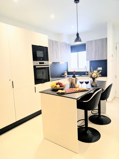Modern kitchen with cream cabinetry, black countertop island, and blue backsplash at Manage Home Tenerife apartment in Costa
