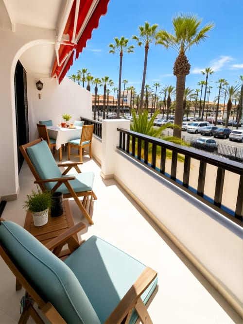 Sunny balcony with lounge chairs overlooking palm trees and parking at Playa de las Américas apartment