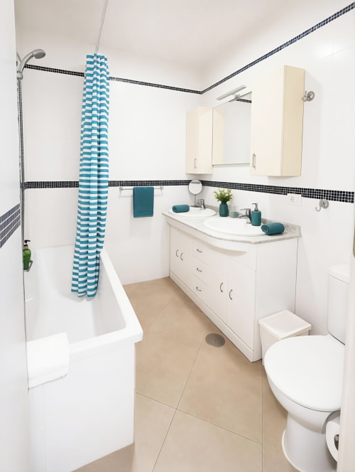 Modern bathroom in Playa de las Américas apartment with white vanity, blue striped shower curtain, and black tile accents