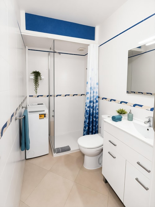 Modern bathroom with glass shower enclosure, white vanity, and blue accents at Manage Home Tenerife apartment in Playa de las