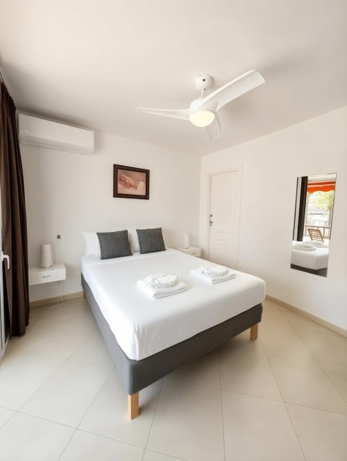 Modern bedroom in Playa de las Américas apartment with queen bed, ceiling fan, air conditioning, and balcony access