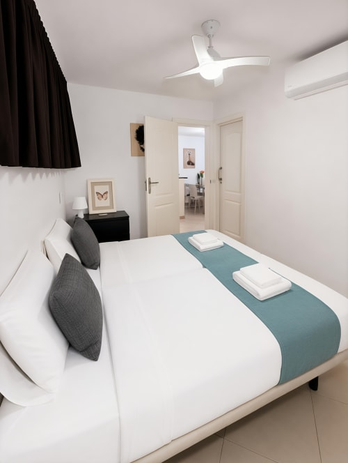 Modern bedroom at Manage Home Tenerife apartment in Playa de las Américas with white bed, teal runner, ceiling fan and air