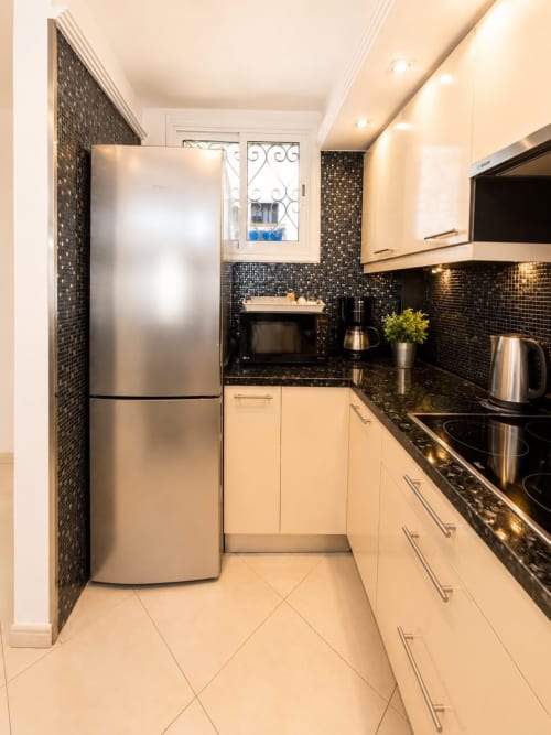 Modern kitchen in Playa de las Américas apartment with cream cabinets, black mosaic backsplash, stainless steel appliances