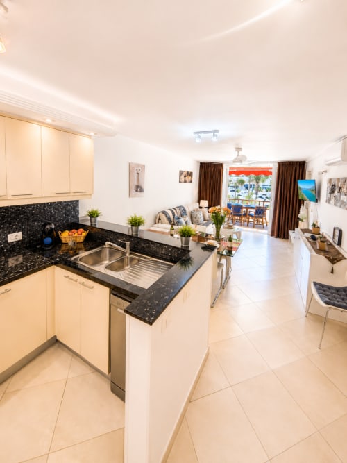 Modern kitchen with black granite counters, cream cabinets, and island in Playa de las Américas apartment