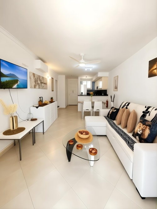 Modern living room with white sofa, glass coffee table, and TV at Manage Home Tenerife apartment in Playa de las Américas