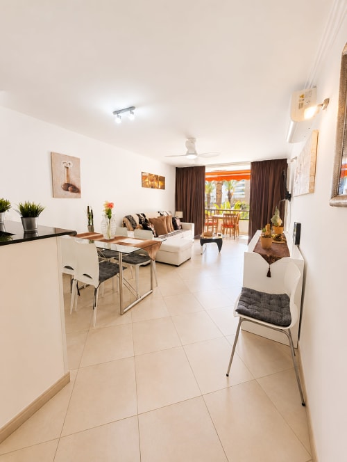 Modern apartment in Playa de las Américas with open living room, dining area, kitchen, and balcony with city views
