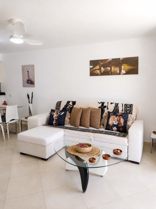 Modern living room in Playa de las Américas apartment with cream sofa, glass table, and wildlife artwork