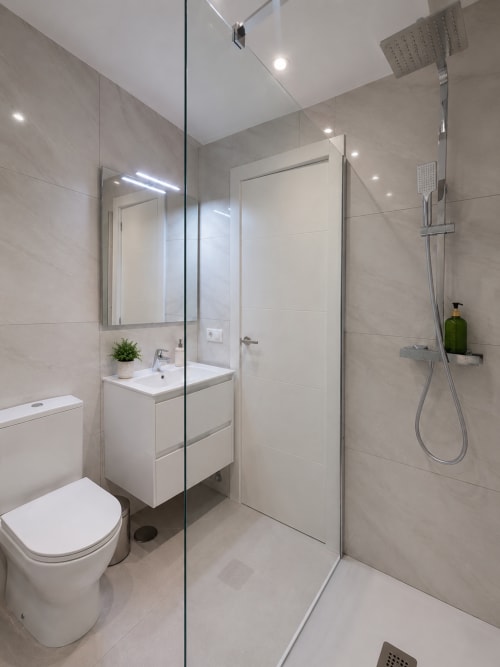 Modern bathroom in Playa de las Américas apartment with walk-in shower, vanity sink, and heated floor lighting