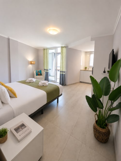 Modern studio apartment in Playa de las Américas with queen bed, green accents, and city views