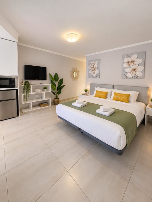 Modern studio apartment in Playa de las Américas with queen bed, kitchenette, TV, and decorative floral artwork