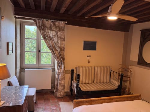 Chambre douillette aux Gîtes Changy Tourny avec poutres apparentes, lit en fer, coussins rayés et vue sur le jardin