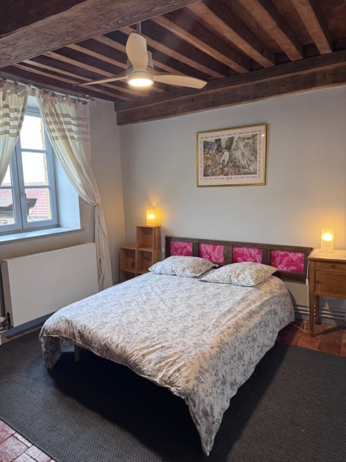 Chambre aux Gîtes Changy Tourny avec lit queen, poutres apparentes, tête de lit rose et vue sur le jardin