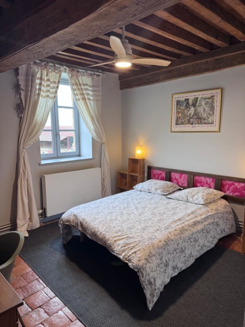 Chambre douillette du gîte Changy Tourny avec poutres en bois, lit queen-size, coussins roses et vue sur le jardin