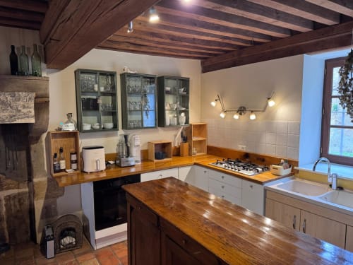 Cuisine contemporaine au Gîte La Maison du Petit Louis avec poutres en bois, cuisinière à gaz et vue sur le jardin