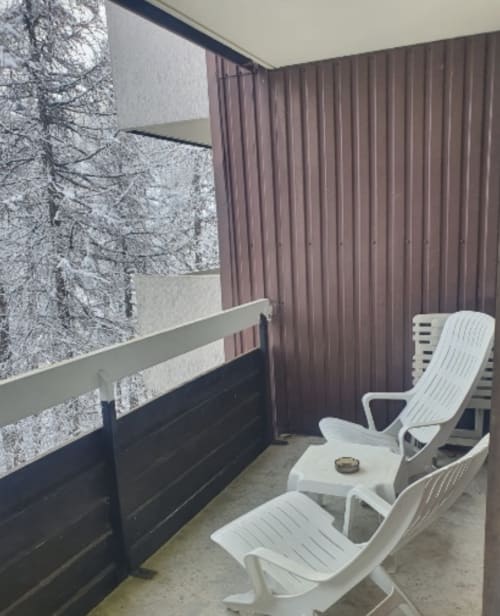 Balcon enneigé de la montagne à l'appartement GNM à Vars, chaises longues blanches et rideaux marron