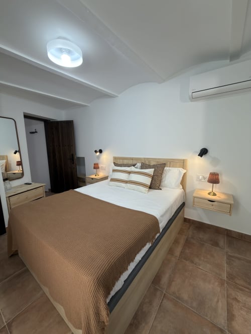 Habitación moderna en Casa La Almedina B&B en Casarabonela con cama de madera, sábanas blancas, mesitas de noche y techo empotrado