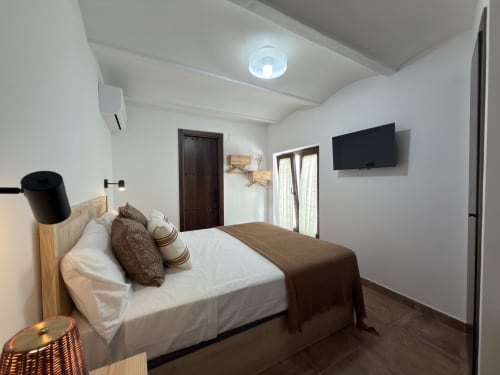 Dormitorio moderno en Casa La Almedina de Casarabonela con cama, TV, aire acondicionado y luz natural abundante