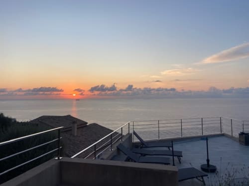 Vue du coucher de soleil depuis la terrasse de la villa avec piscine chauffée à San-Martino-di-Lota, vue mer et chaises longues