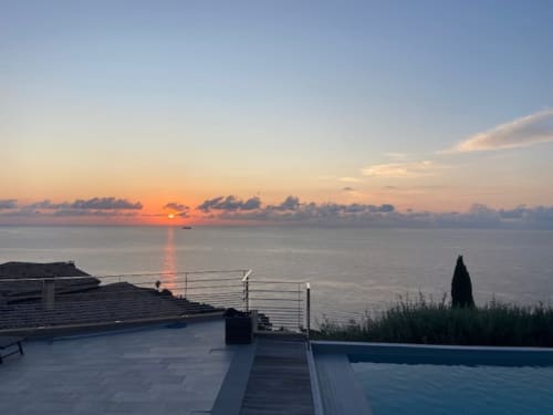 Vue coucher de soleil depuis la terrasse de la piscine chauffée de la villa Altezza à San-Martino-di-Lota avec panorama marin et cyprès