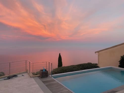 Vue au coucher de soleil depuis la piscine chauffée privée de la Villa Altezza dominant la mer à San-Martino-di-Lota, Corse