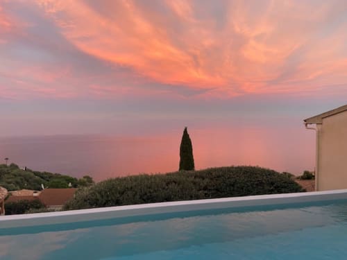 Vue du coucher de soleil depuis la piscine chauffée de la villa Altezza à San-Martino-di-Lota avec vue panoramique sur la mer et cyprès