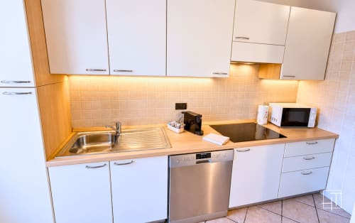 Cucina moderna con armadi bianchi, piano di lavoro in legno e elettrodomestici in acciaio inox presso l'appartamento Hometoday a Padova, Italia