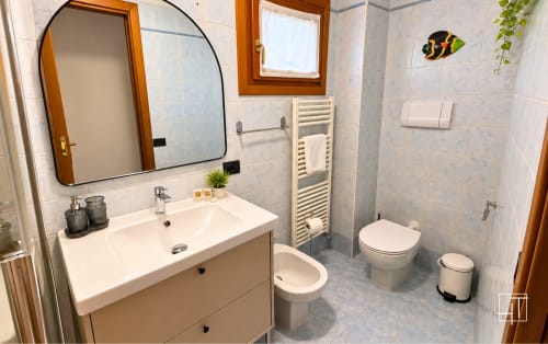 Bagno moderno dell'appartamento Hometoday a Padova con lavabo bianco, water, bidet, scaldasalviette e specchio ad arco