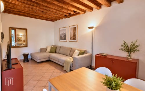 Soggiorno moderno a Padova con divano componibile beige, soffitto con travi in legno e arredamento con vista sul giardino presso Hometoday