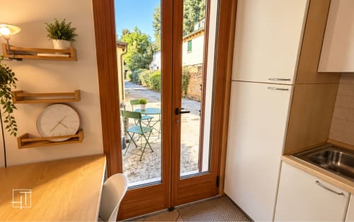 Cucina moderna di appartamento che si apre su patio giardino a Padova, Italia con porte in legno, lavello in acciaio inossidabile e scaffalature a muro