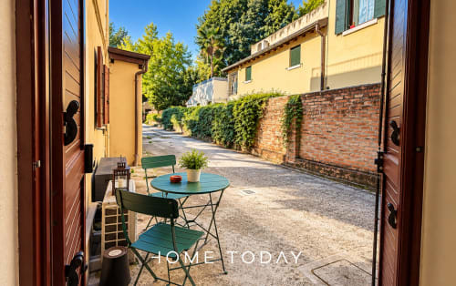 Affascinante cortile-giardino dell'appartamento Hometoday a Padova con arredi verdi e muri in mattoni ricoperti di edera