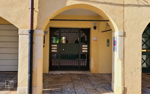Ingresso ad arco giallo dell'appartamento Hometoday a Padova con cancello verde e cortile piastrellato