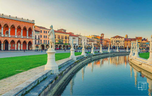 Piazza storica di Padova con architettura rinascimentale, prato verde, canale e statue bianche nel centro della città italiana